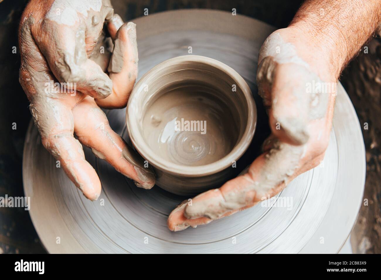 Potter's hands working clay on a potter's wheel Stock Photo