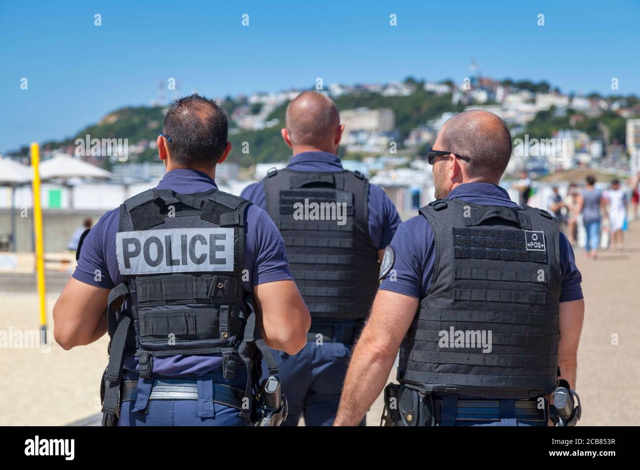 Le Havre, France - August 05 2020: Group of policemen in bulletproof vest patrolling at the beach. Stock Photo