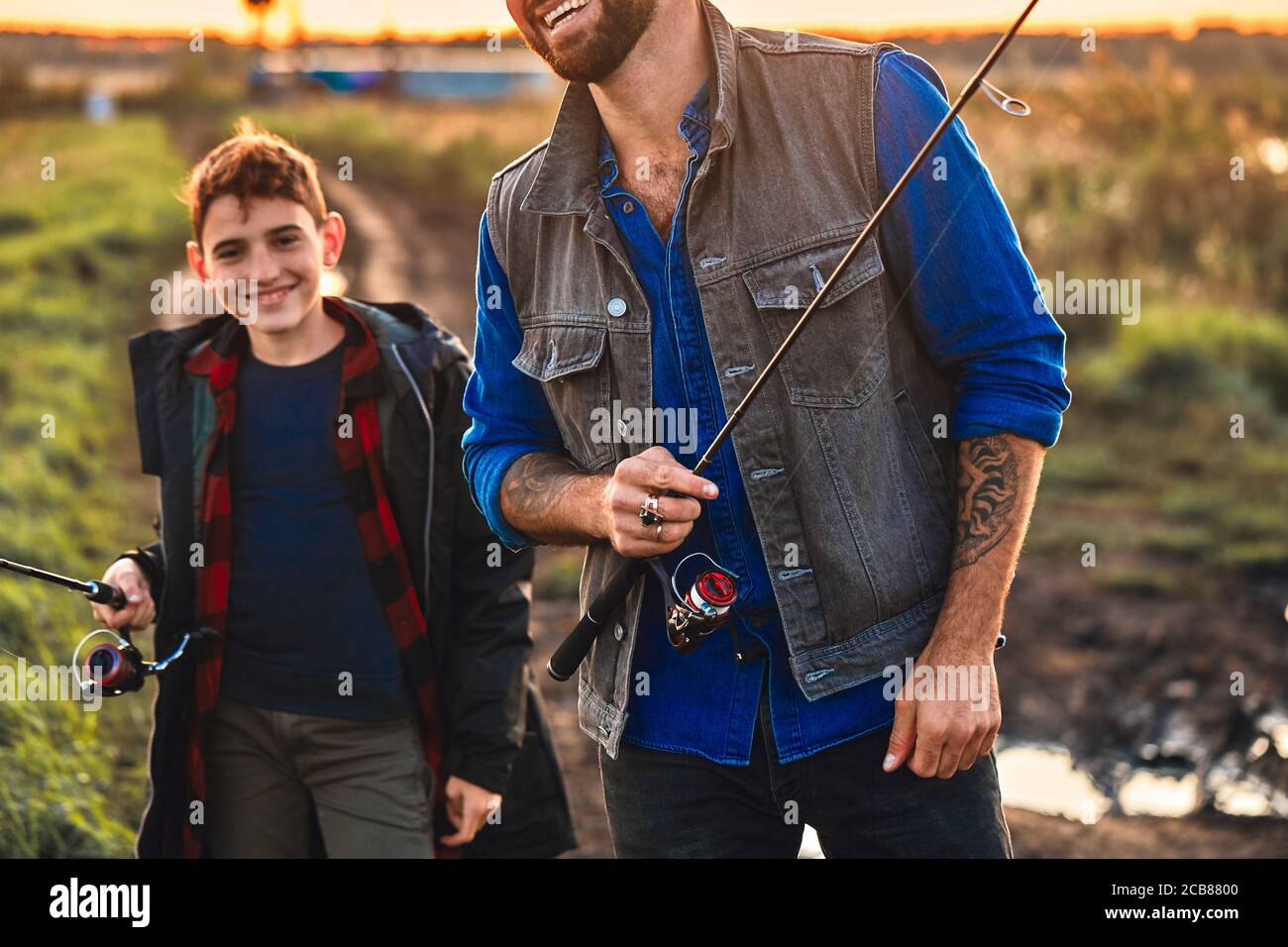 Happy father and son go to fishing place, they take fishing rods and ...