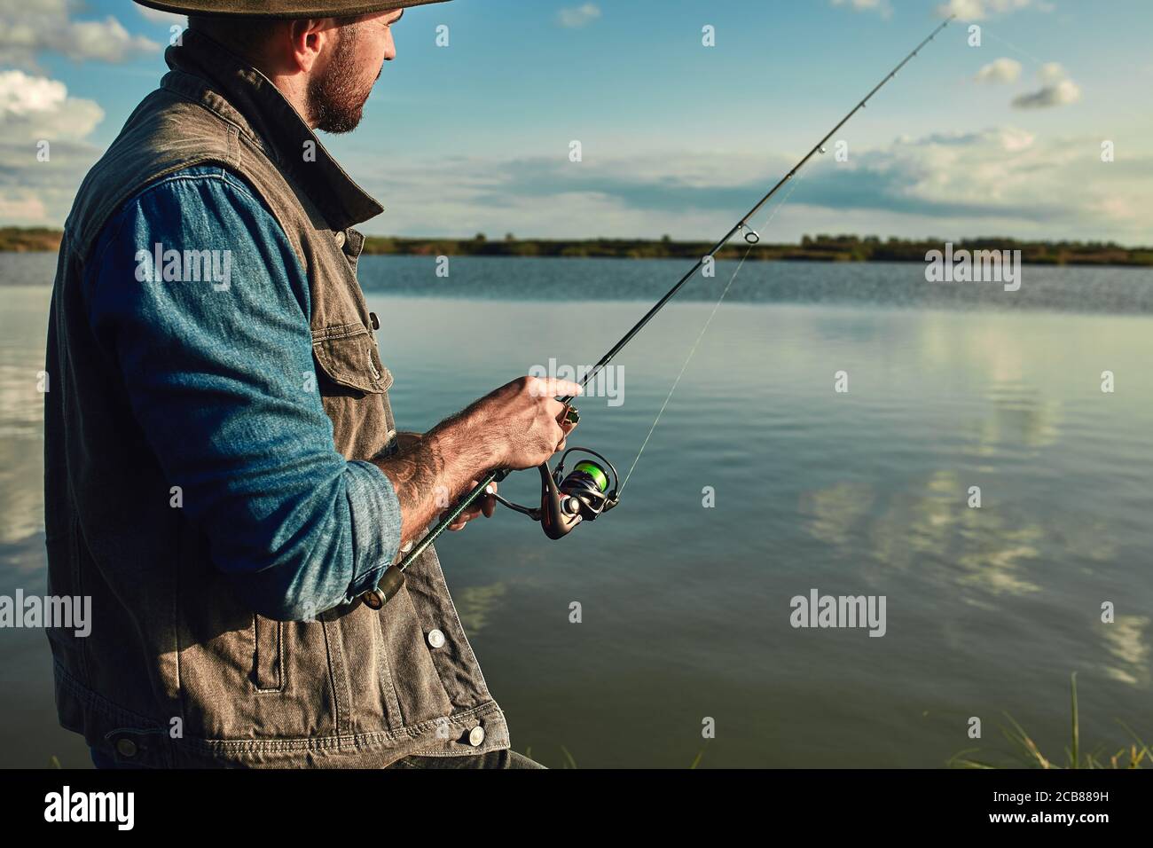 https://c8.alamy.com/comp/2CB889H/caucasian-adult-bearded-men-stand-near-lake-and-hold-fishing-rod-he-looks-into-distance-and-at-float-fishing-is-meditation-2CB889H.jpg