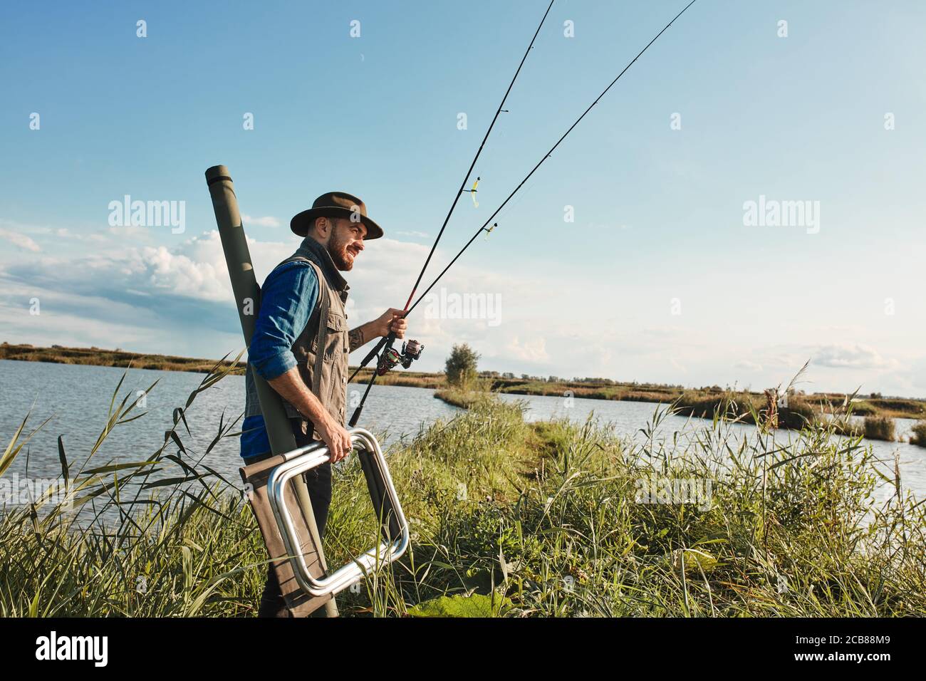 https://c8.alamy.com/comp/2CB88M9/adult-caucasian-fisherman-inspects-place-for-fishing-hold-tackle-fishing-stool-warm-and-sunny-day-background-blue-lake-2CB88M9.jpg