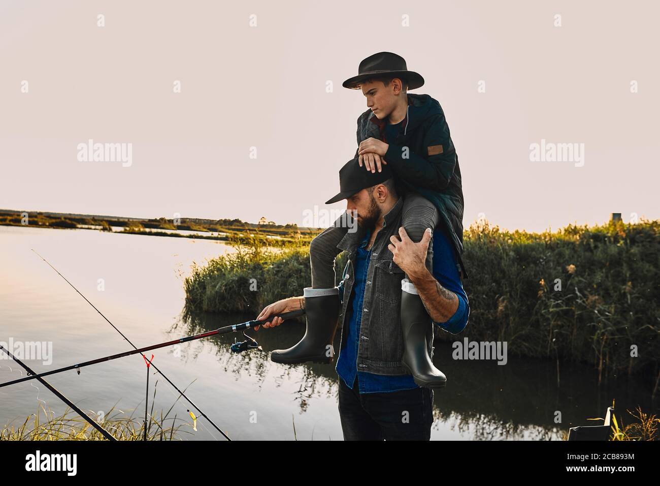 Father and son have fun while fishing. Teen boy sit on father