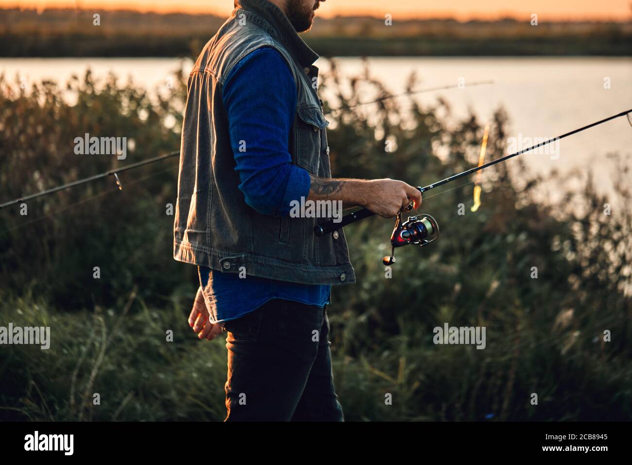 https://c8.alamy.com/comp/2CB8945/caucasian-adult-bearded-men-stand-near-lake-and-fish-sunset-2CB8945.jpg