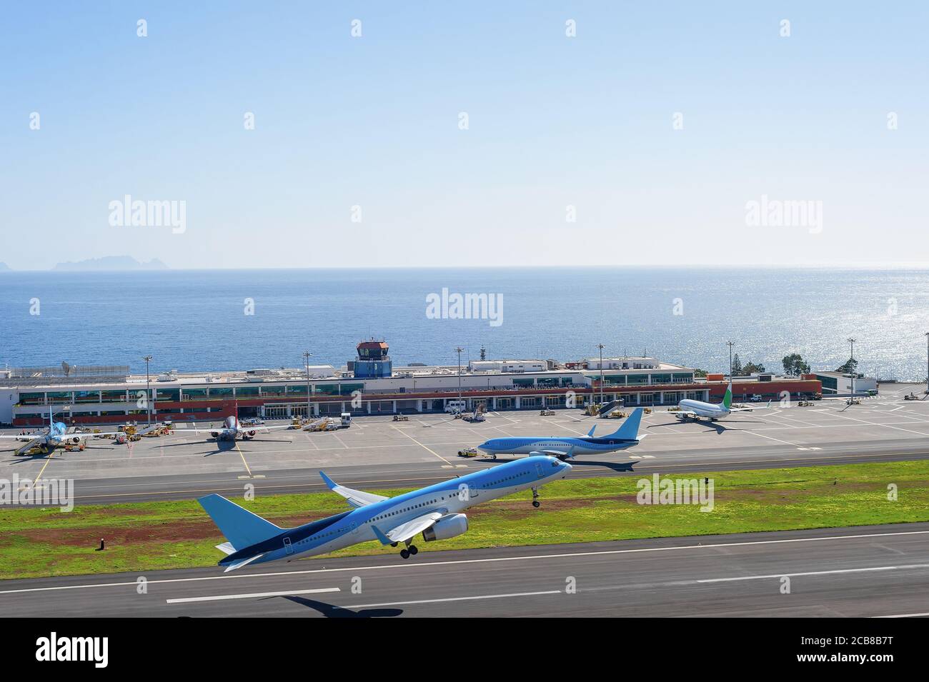 Airplanes taking off at runway of Madeira International Airport, bright sunshine weather, ocean view in background, Funchal, Portugal Stock Photo