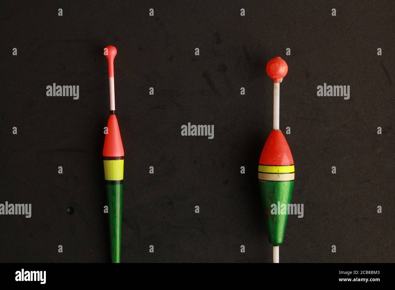 Top view of two colorful fishing rod bobbers on a black background