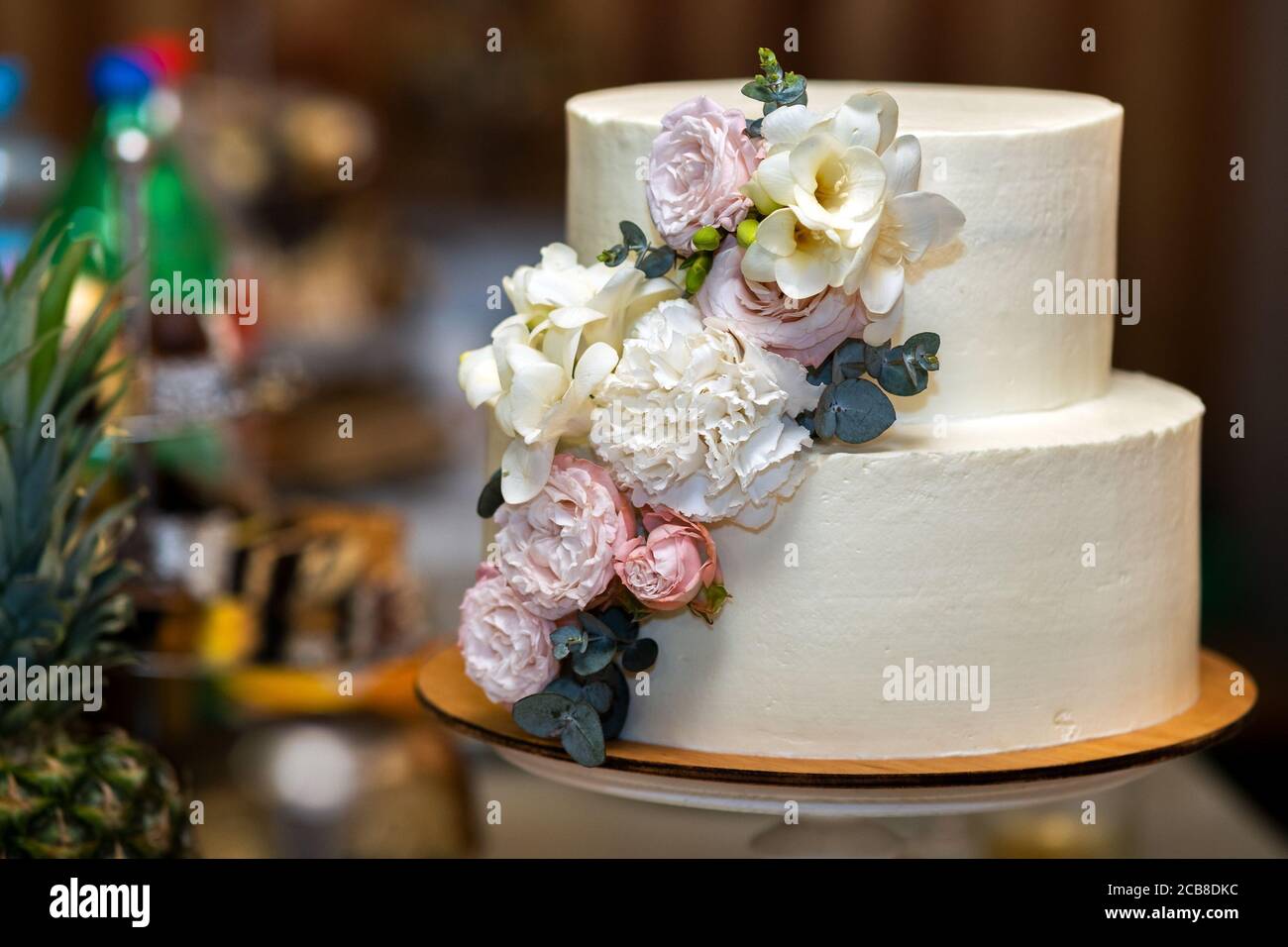 Tall sweet wedding cake decorated with live pink and white flowers on a ...