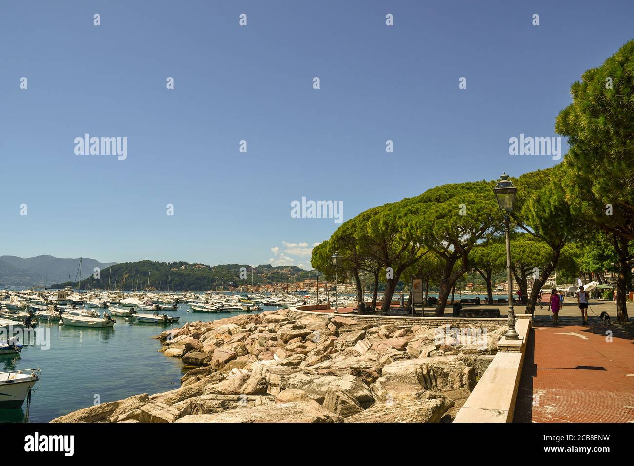 View of the seaside promenade with people walking and the harbor of the sea town on the shore of the Gulf of the Poets, Lerici, La Spezia, Italy Stock Photo