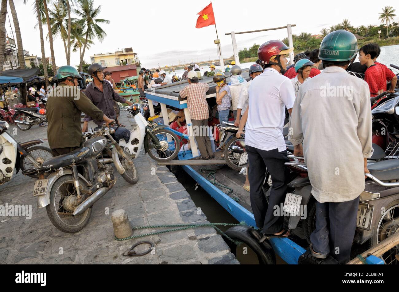 Passengers and bikers boarding a ferry in Hoi An, Vietnam Stock Photo