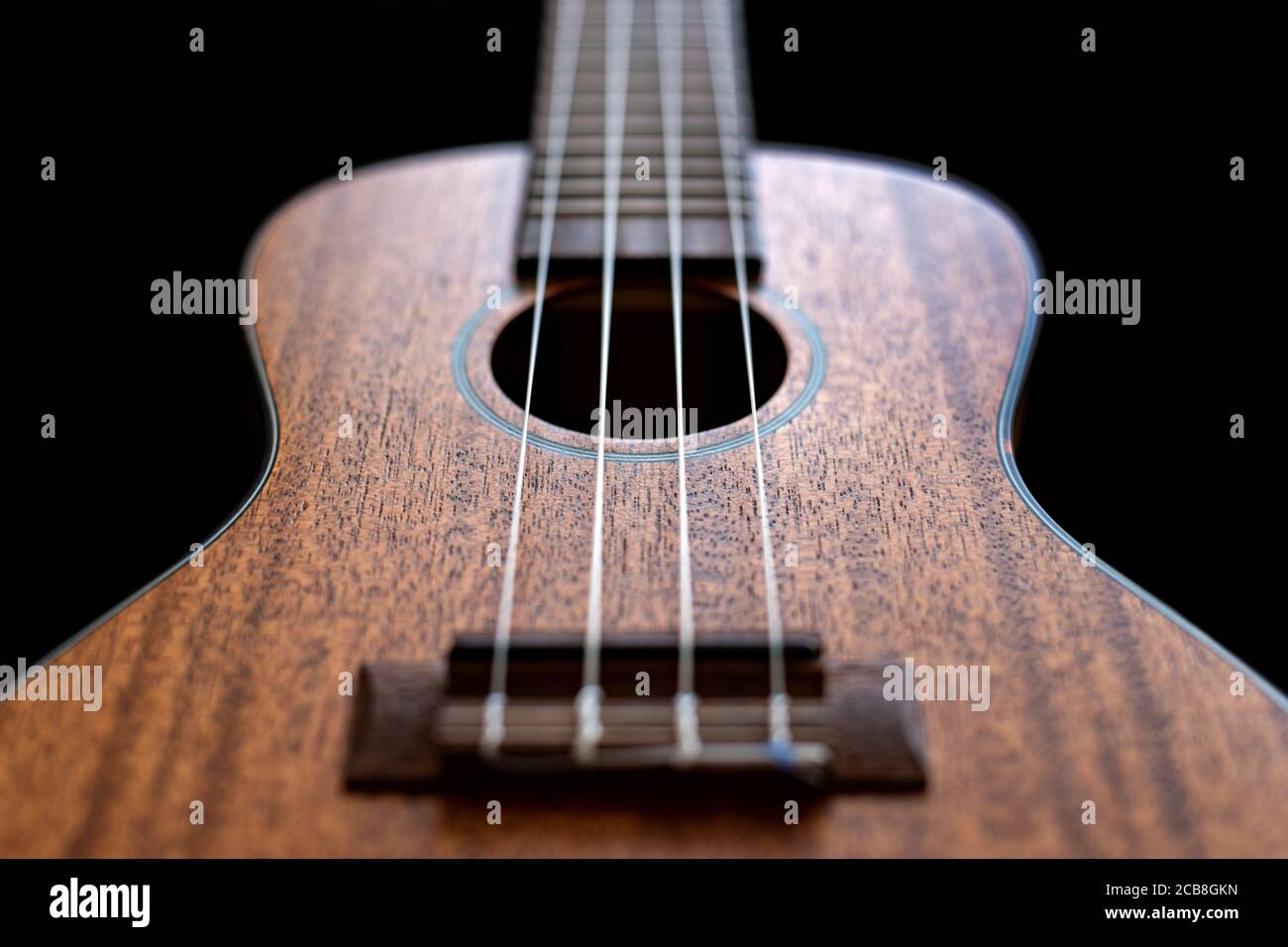 Close up view of a wooden ukulele body isolated on a black background. Stock Photo