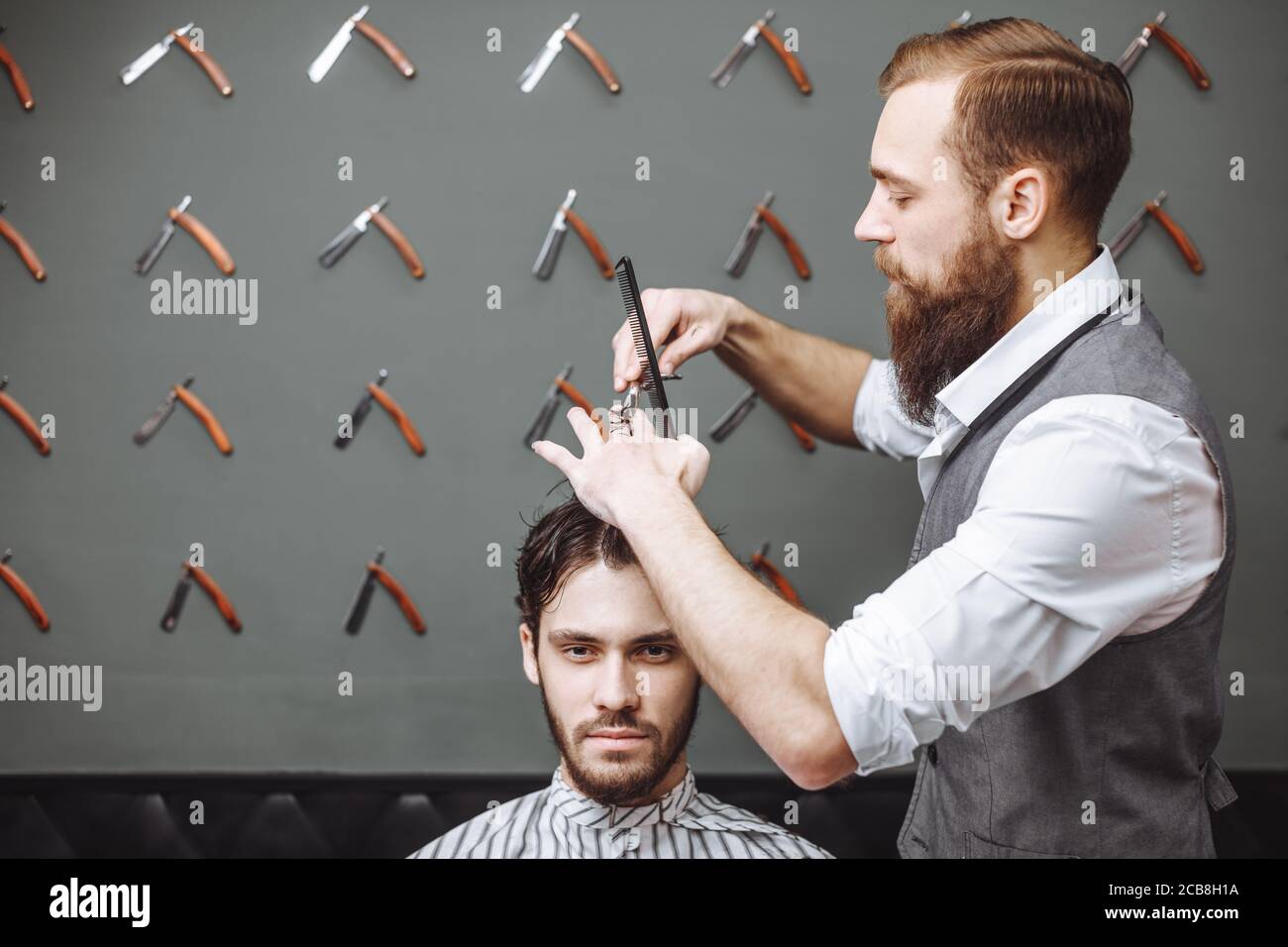Working process in modern barbershop. Male hairdresser serving client ...