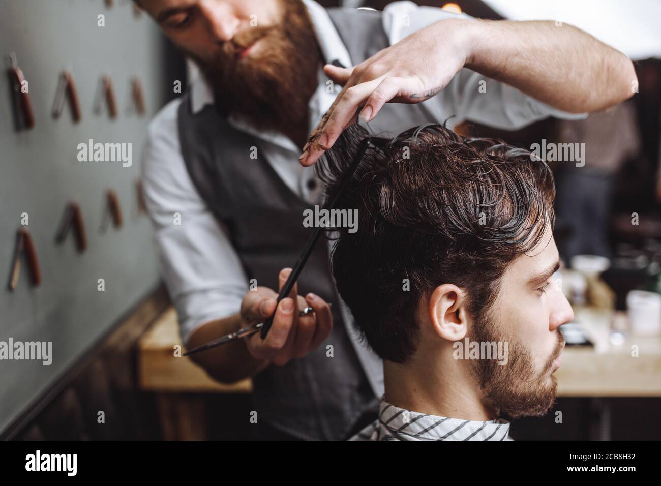 Barber using scissors and comb. Man with beard getting haircut in barber  shop. Modern hair salon concept Stock Photo - Alamy