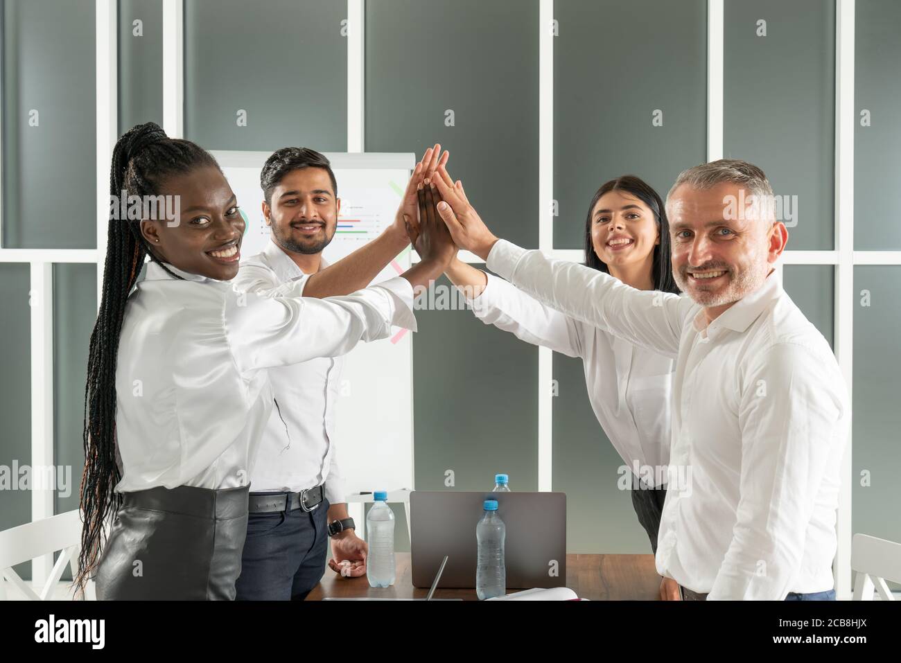 Teamwork concept. Happy successful multiracial business team giving a high fives gesture as they laugh and cheer their success Stock Photo