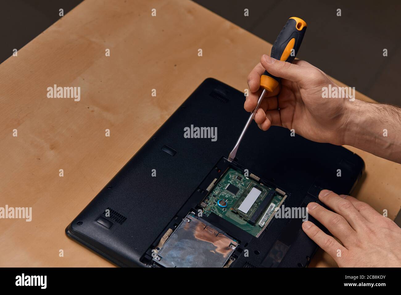 attractive hard working guy dismantling laptop with screwdriver ...