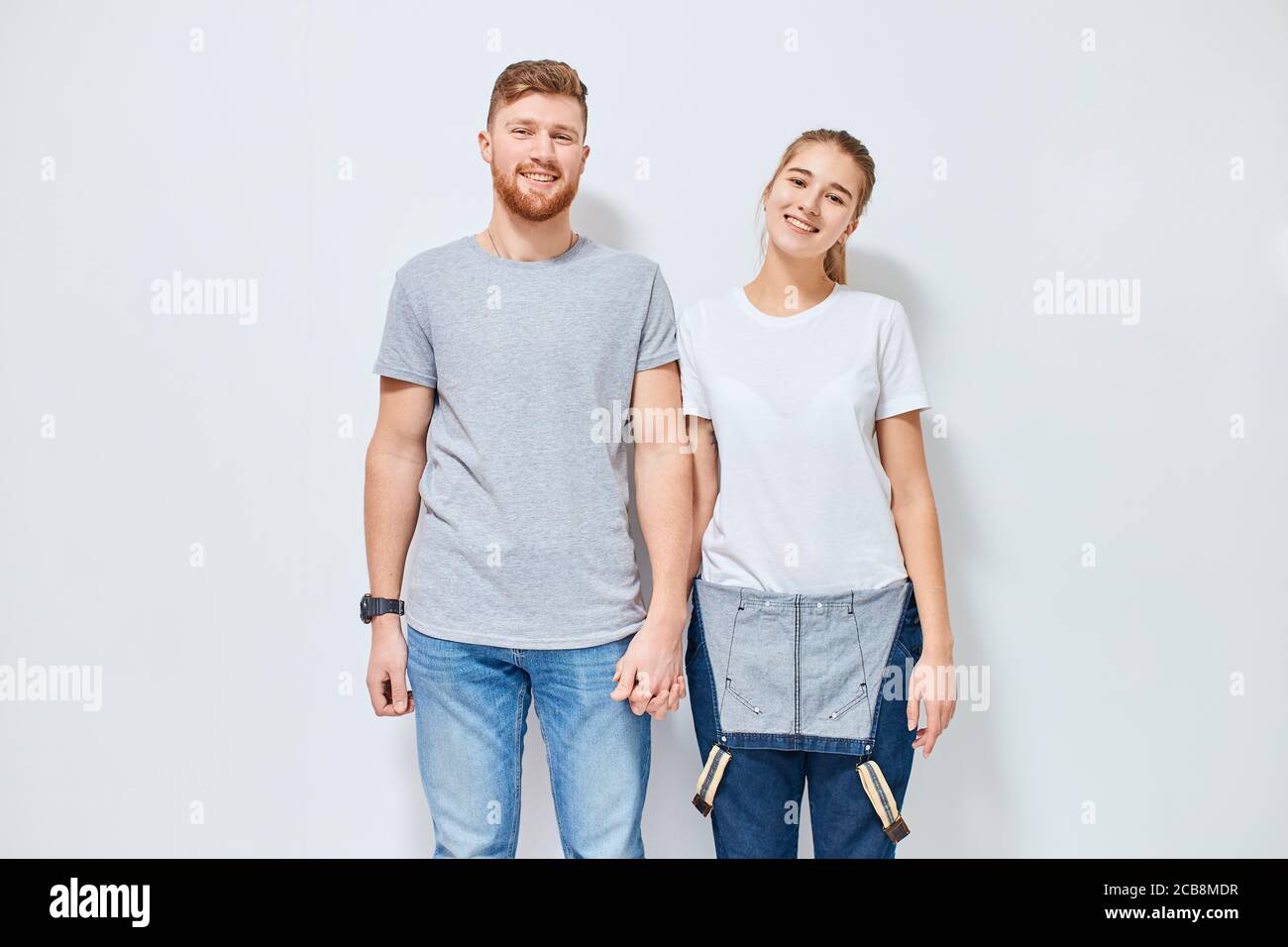 Cute young happy couple in love smiling holding hands looking at camera ...