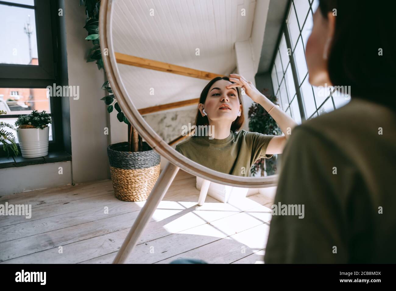 Attractive young caucasian woman touching face and looking at mirror ...