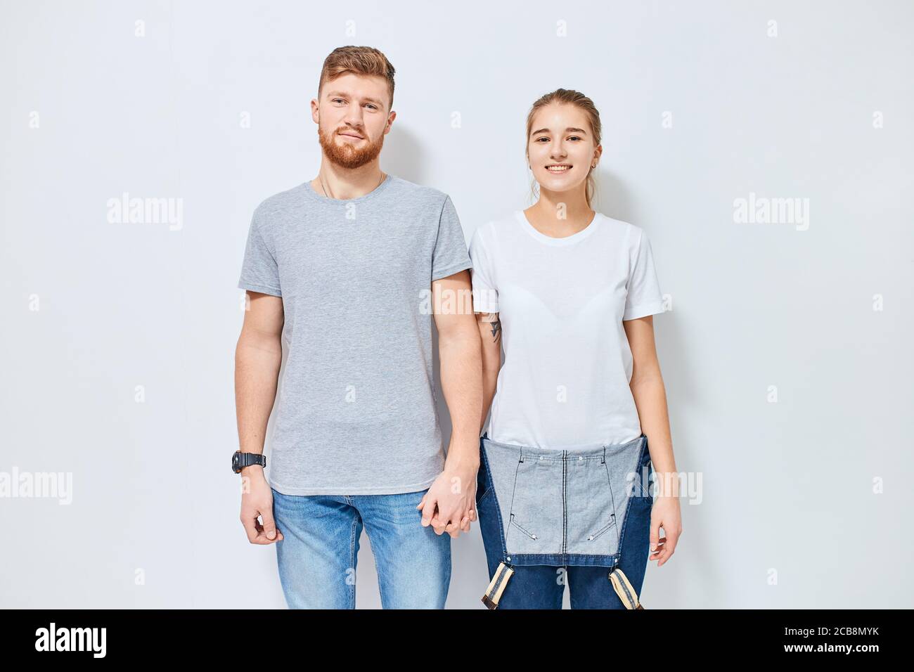 Cute young happy couple in love smiling holding hands looking at camera ...