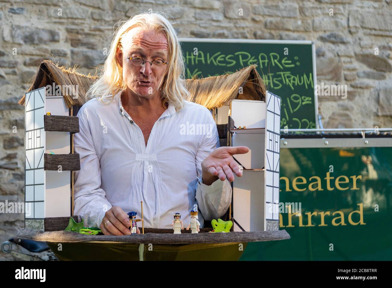 Mülheim an der Ruhr, Germany. 7 August 2020. Broicher Schlossnacht 2020 on 7 and 8 August takes place with a social distancing concept because of coronavirus / Covid-19. Jörn Kölling presents an abriged version of Shakespeare from a hawker's tray. Stock Photo