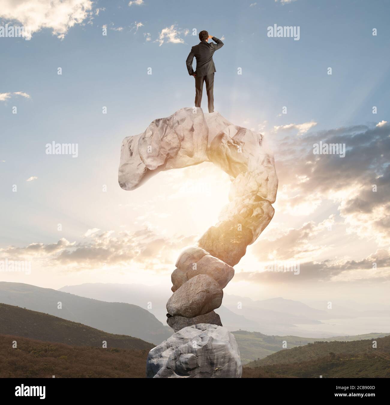 Businessman over a mountain shaped as question mark looks for the future Stock Photo