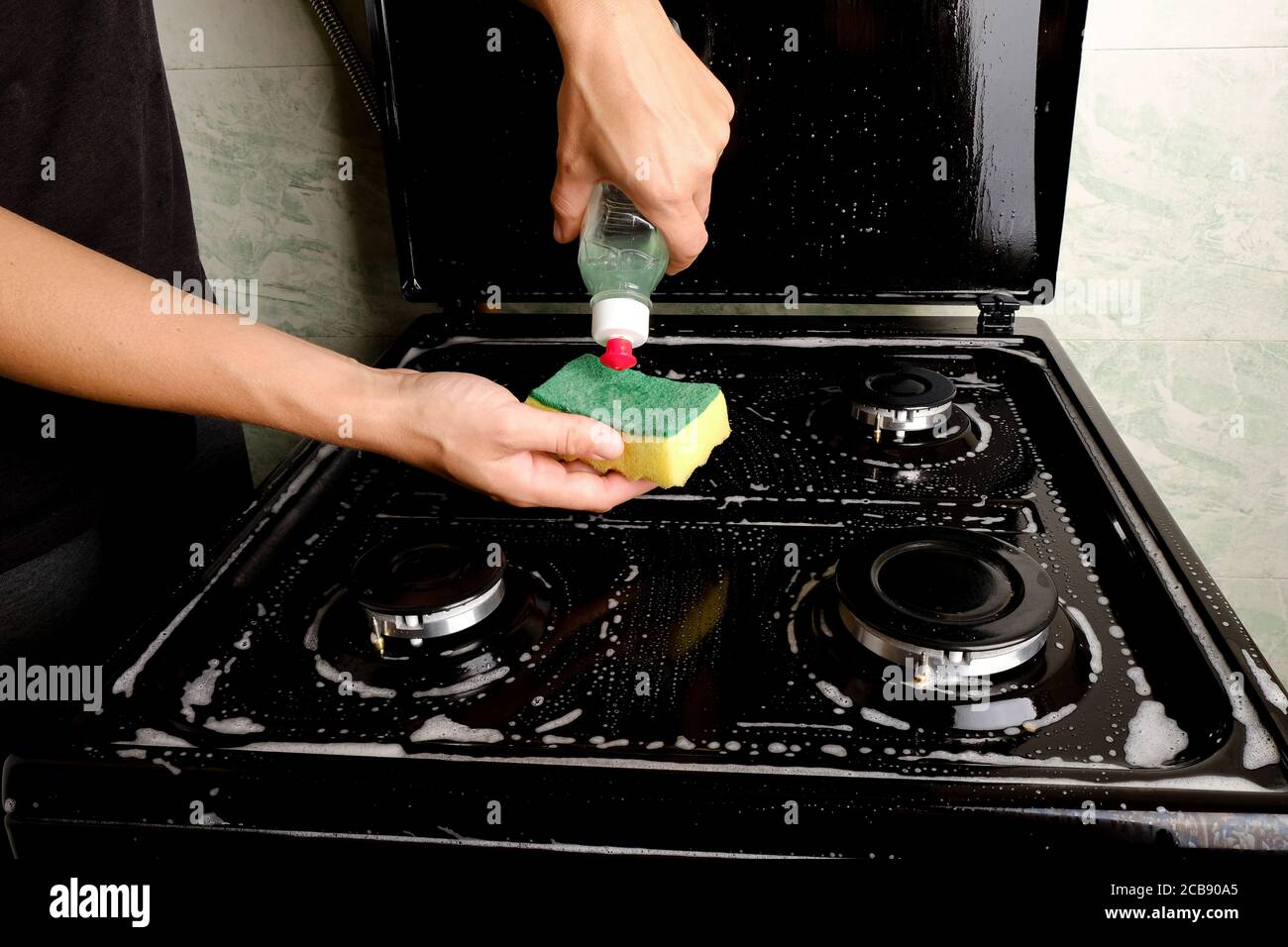 Cleaning the gas stove in the kitchen with detergent and a sponge. Household appliances for