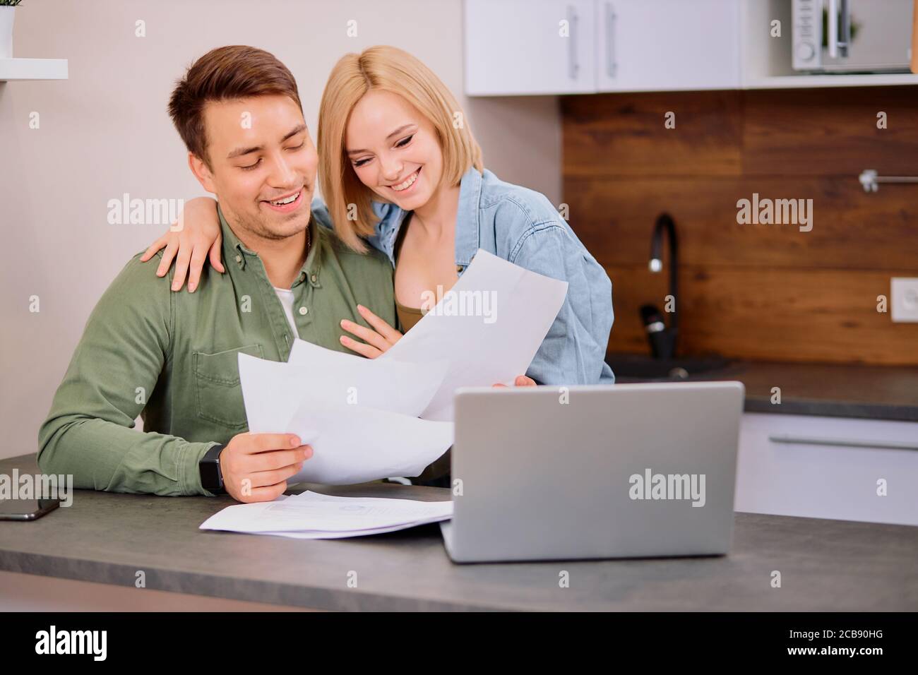 spouses sitting with laptop and documents, analyzing paperwork and house utility bills, financial issues, thoughtful couple consider papers managing f Stock Photo