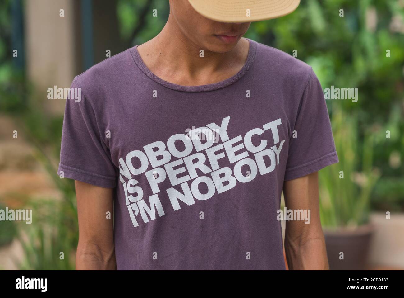 Young man wearing a t-shirt with an inscription saying 'Nobody is Perfect, I'm Nobody'. Stock image. Stock Photo