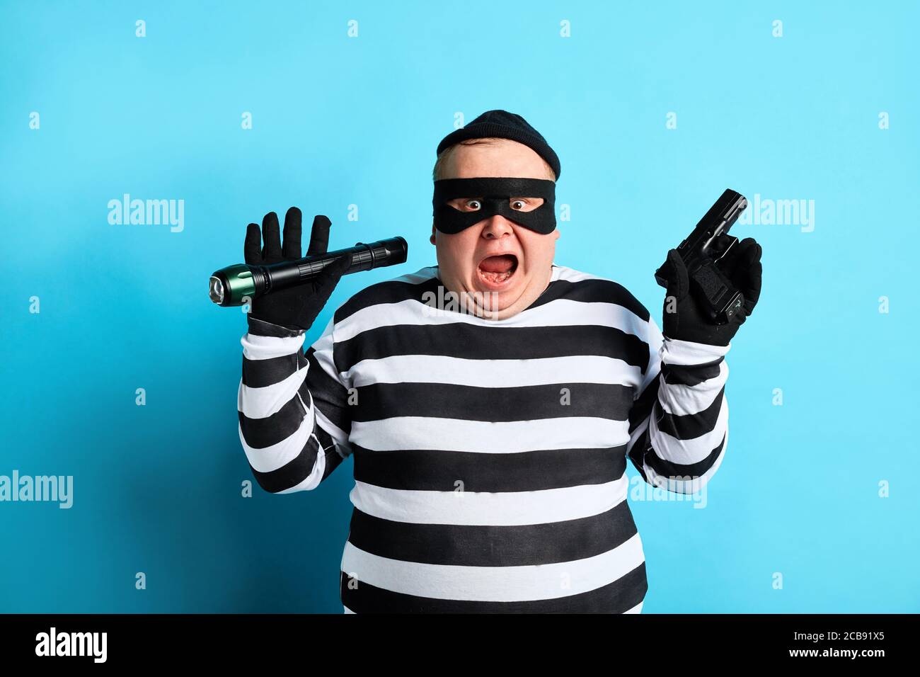 thief with raised arms has decised to turn himself in. close up portrait,isolated blue background. studio shot.calm dowm Stock Photo