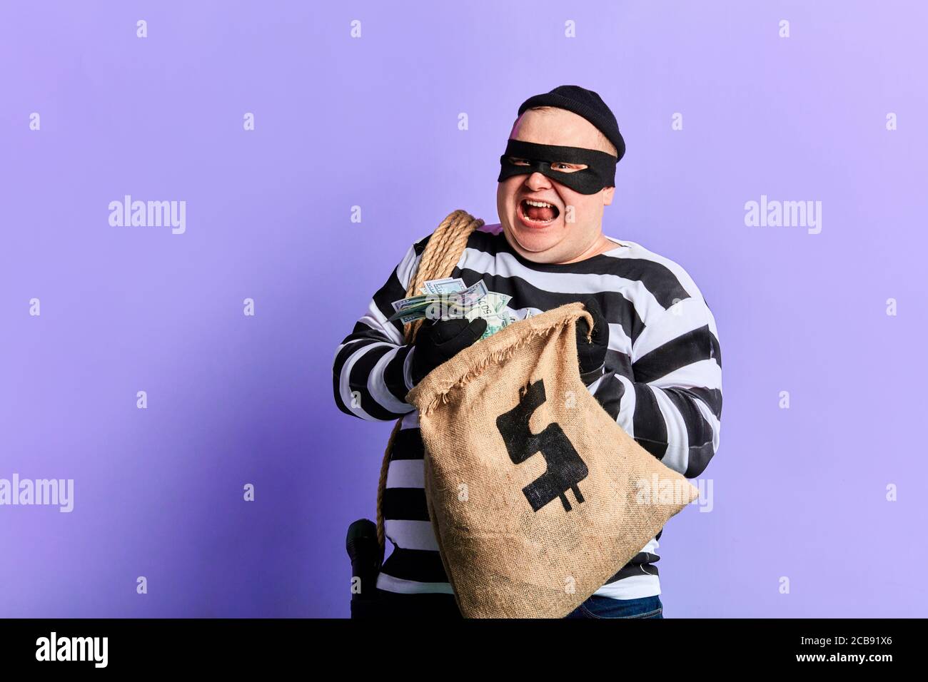 rich prisoner in striped uniform expresses his positive emotion and happiness. isolated blue background Stock Photo