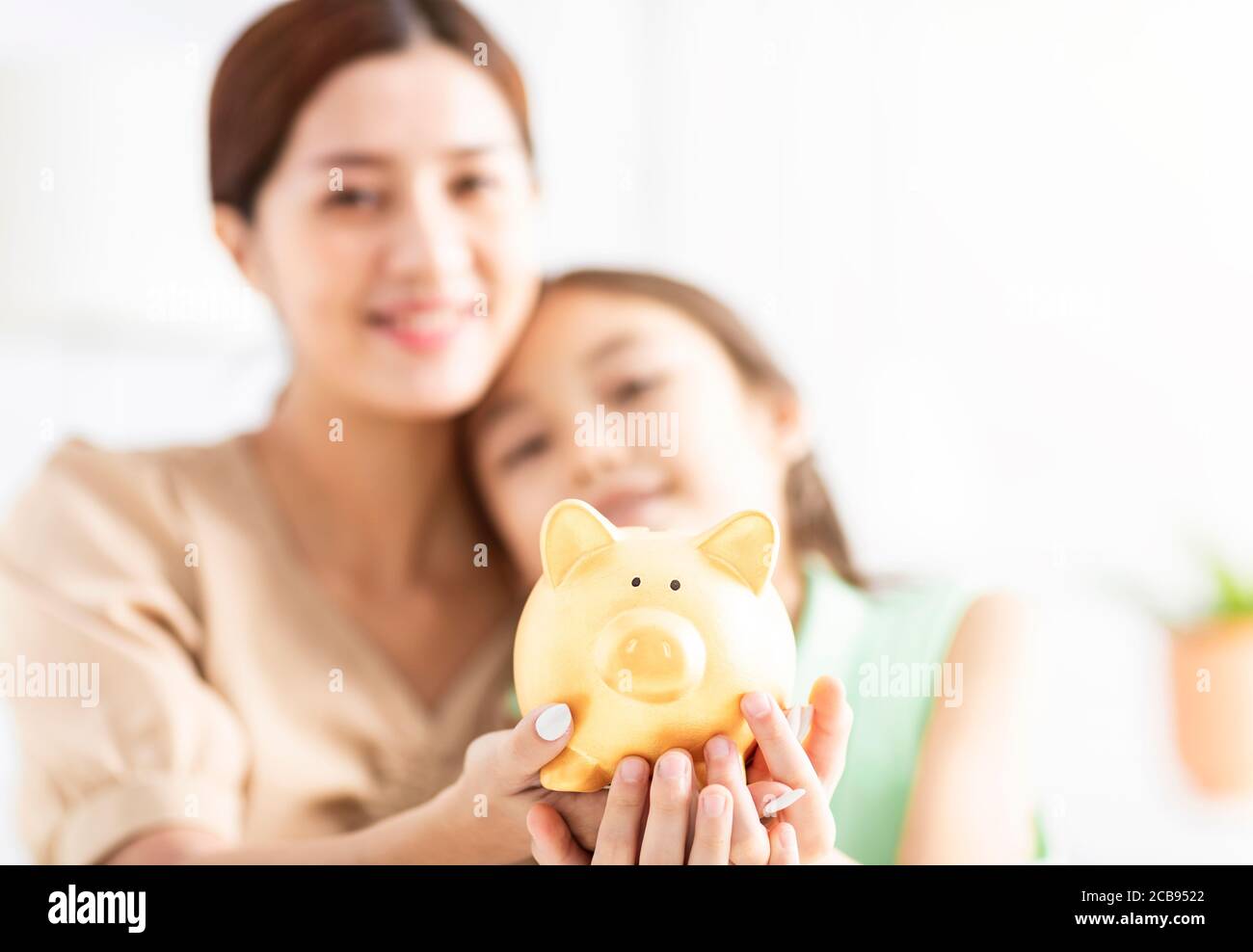 Mother and her daughter holding piggy bank Stock Photo - Alamy