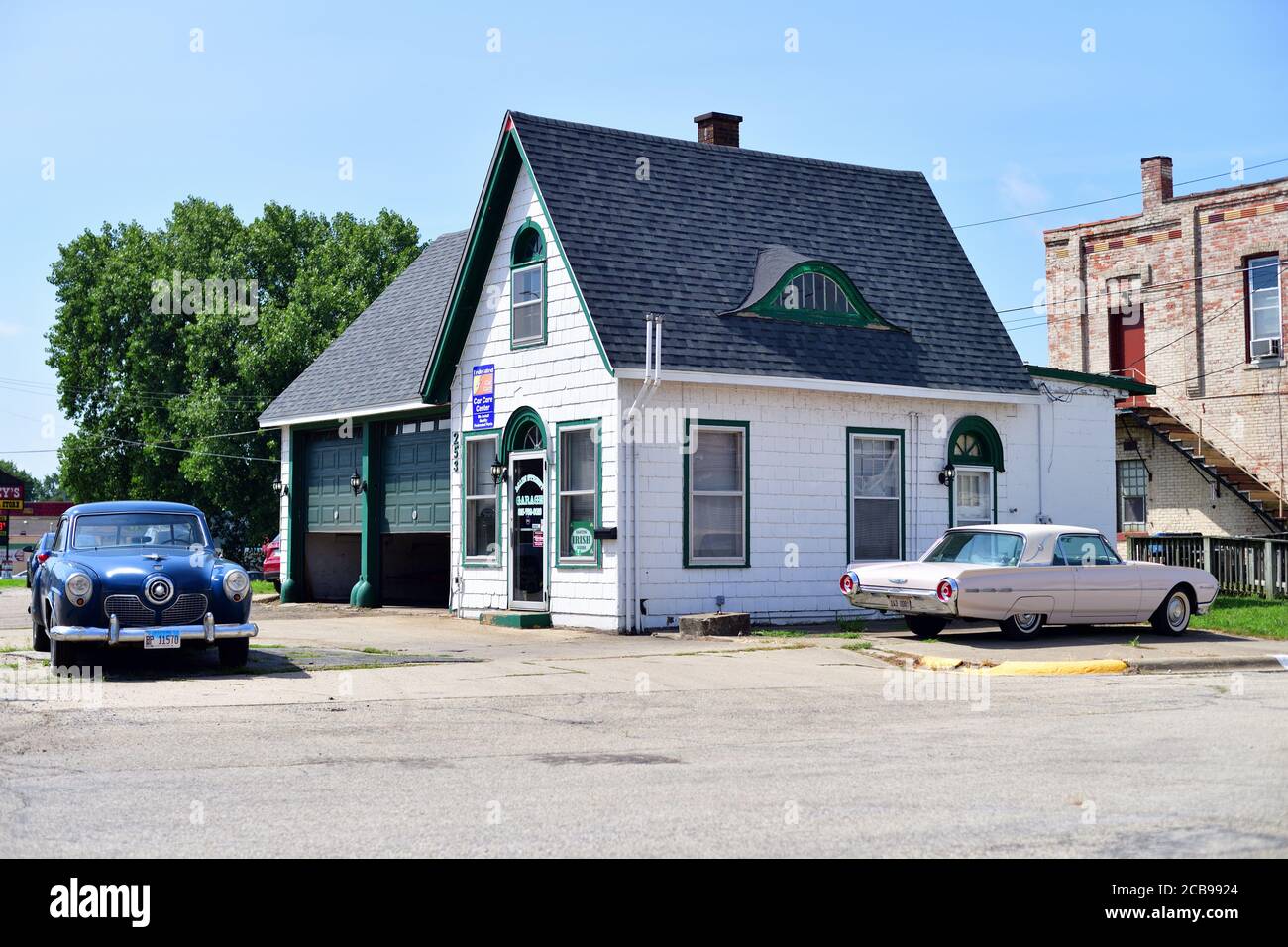 Seneca, Illinois, USA. An old garage with two antique vehicles parked on the property including a 1951 Studebaker and an antique Ford Thunderbird. Stock Photo