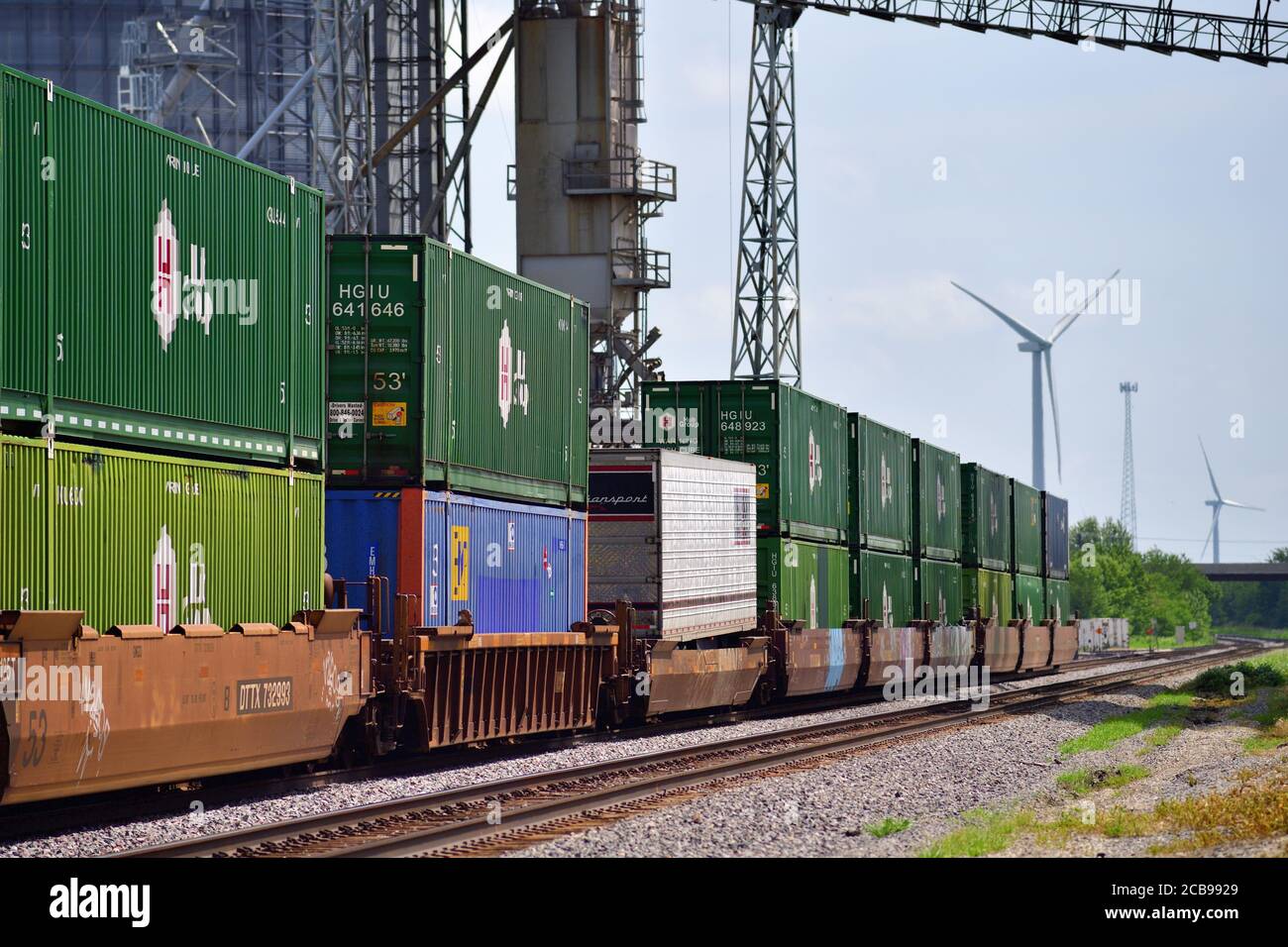 Ransom, Illinois, USA. A Burlington Northern Santa Fe intermodal or stack train passes by and under a large farmer's cooperative complex. Stock Photo