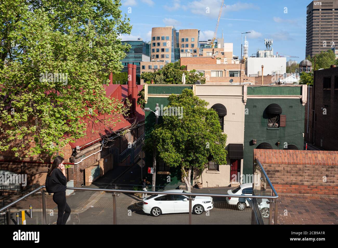 26.09.2019, Sydney, New South Wales, Australia - A young woman talks on the phone with the cityscape of the Haymarket suburb in the backdrop. Stock Photo