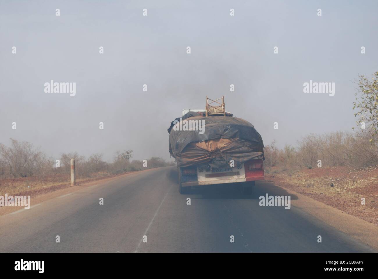A transport truck in Niger, Africa, belches out smoke as it climbs a slight hill. Stock Photo