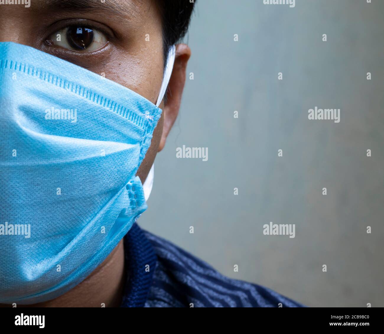 head shot of an Indian man wearing surgical nose mask looking at camera for corona virus or covid-19 protection Stock Photo