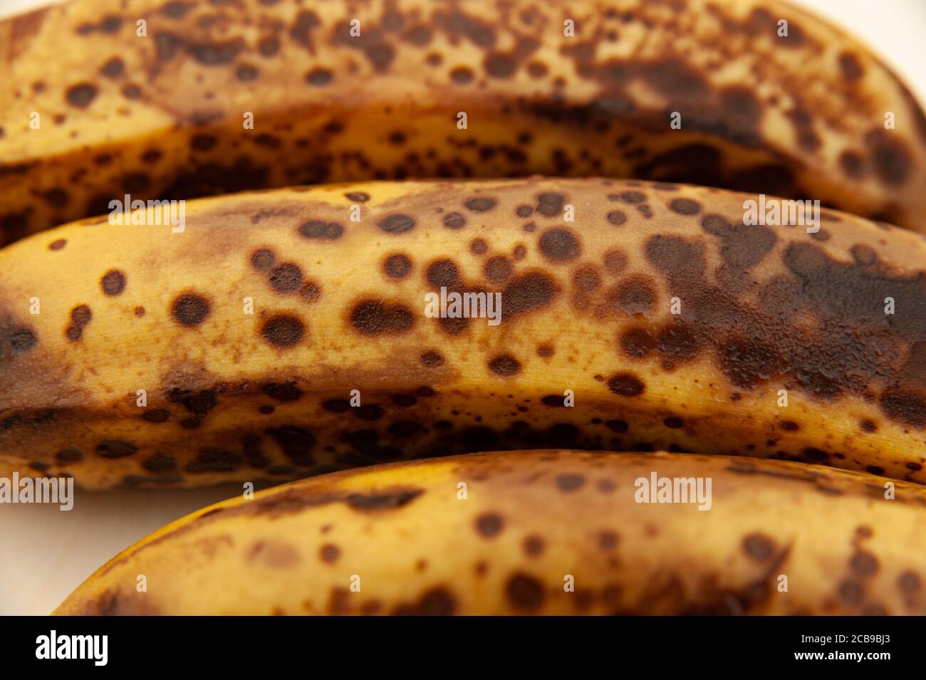 Three ripe bananas isolated on light wooden background. Close-up. Top view. Stock Photo