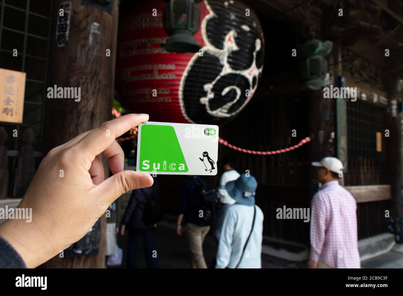 Tokyo, Japan - May 3, 2019 : Man hold Suica pass with the red lantern of Narita-san temple background, Suica is a prepaid card for travelling with tra Stock Photo