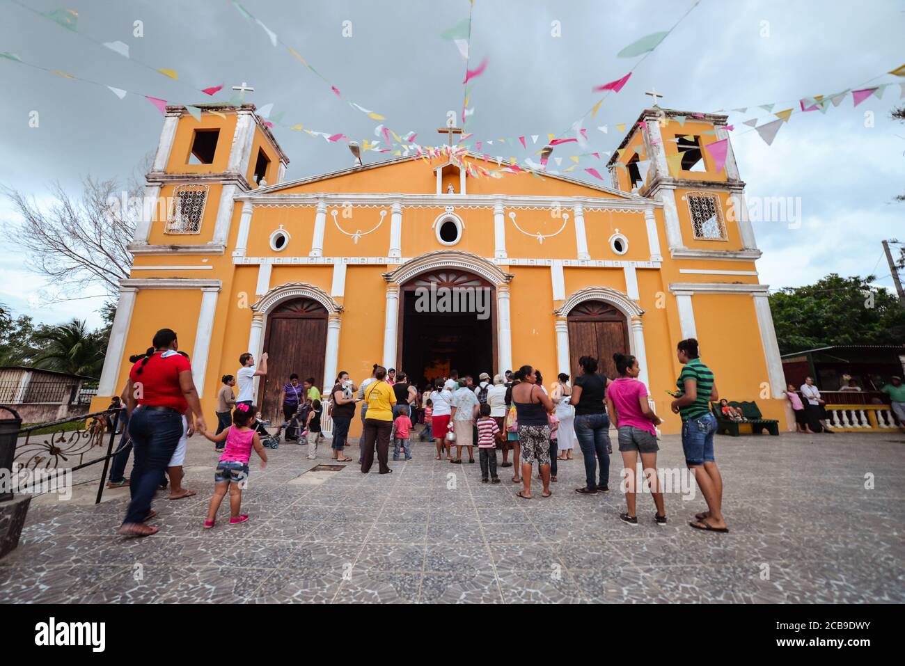 Ometepe Island / Nicaragua - July 15, 2019: Wide angle shot of people entering yellow church in Moyogalpa village Stock Photo