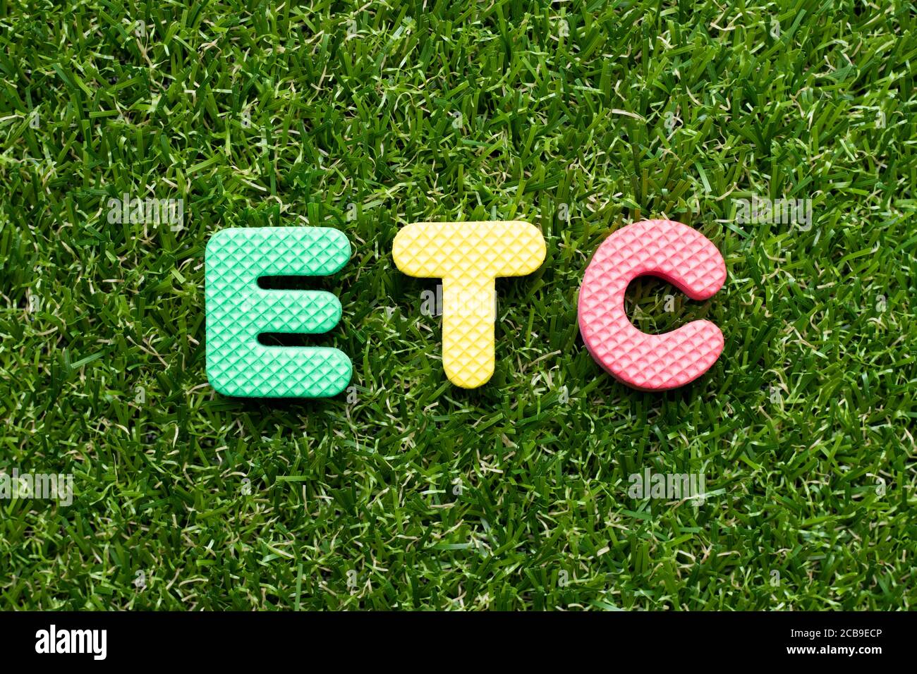 Toy foam letter in word etc (abbreviation of et cetera) on green grass background Stock Photo