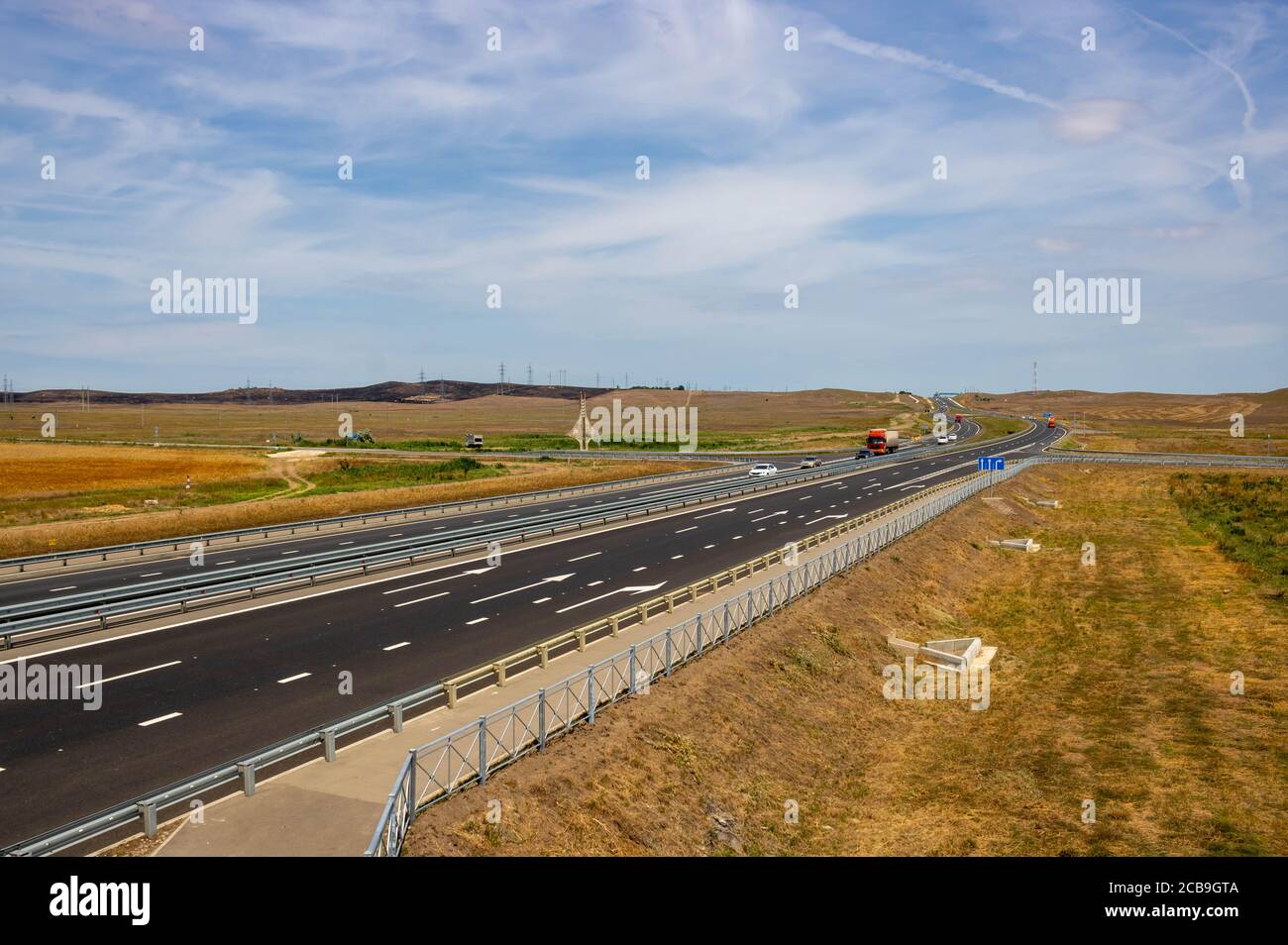highway in steppe against a blue sky,long road stretching out into the distance. Stock Photo
