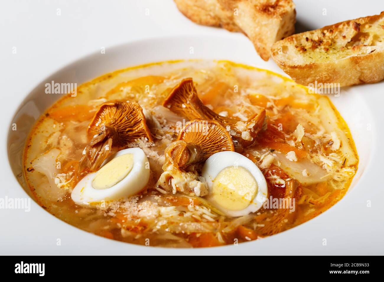 Vegeterian soup with chanterelles and vegetables with fried croutons in a white plate. Delicious recipe with wild mushrooms, organic vegetables and qu Stock Photo