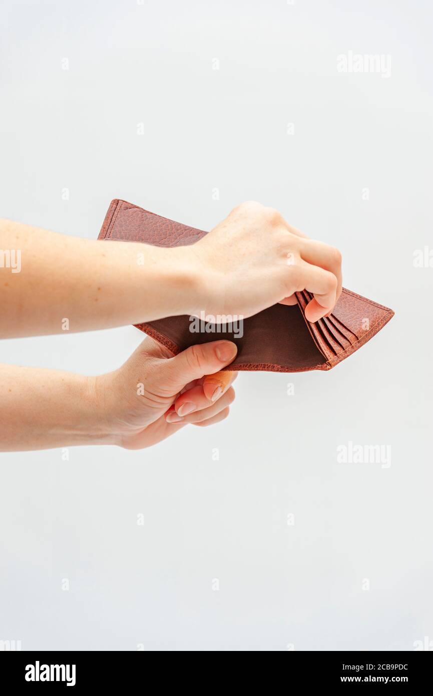 Close-up of hands holding brown leather wallet with no money. Concept: World economic crisis. Isolated on white background. Copy space. Vertical shot. Stock Photo