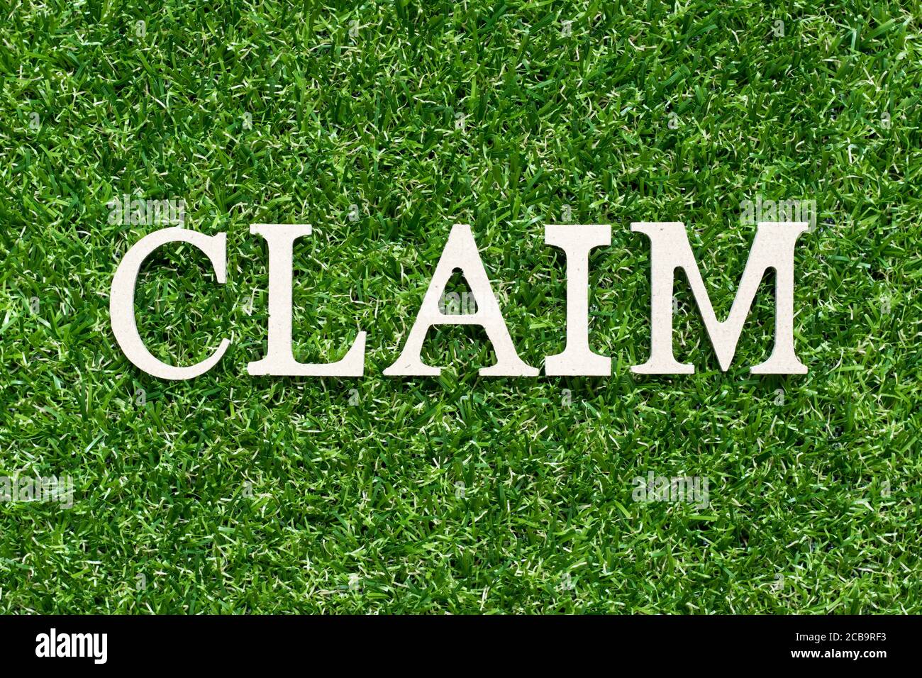Wood alphabet letter in word claim on artificial green grass background ...