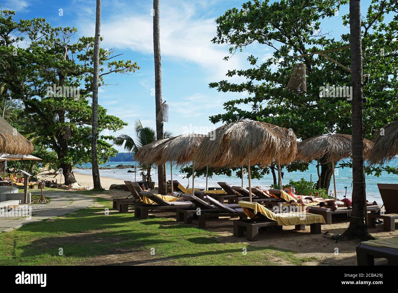 Arrangement and setting of tropical sunbathing daybeds with tourists facing the ocean Stock Photo