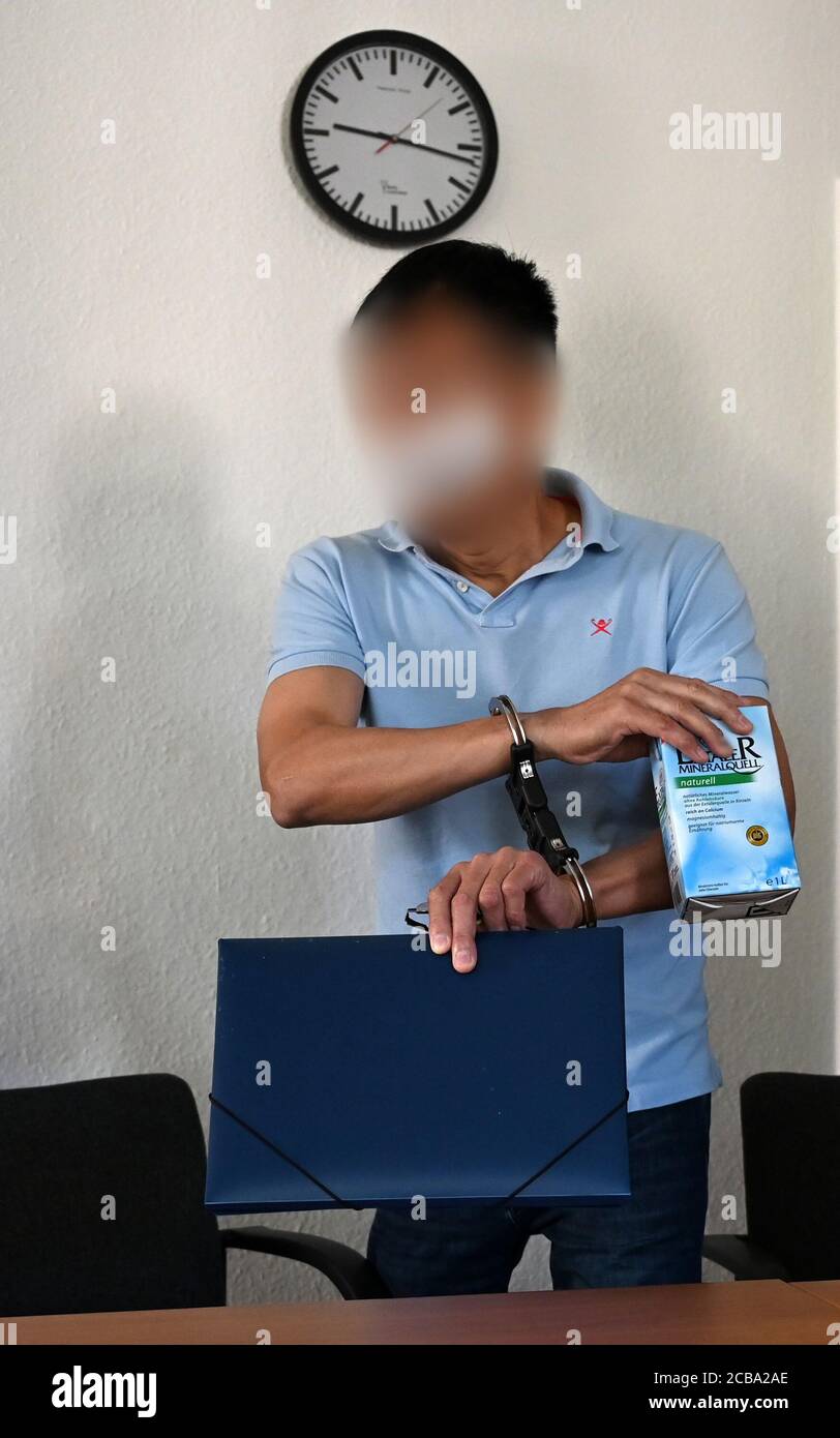 12 August 2020, Saxony, Chemnitz: A man accused of double murder arrives at the Chemnitz Regional Court in the trial room. The accused is said to have strangled two brothers with an electric cable in their apartment in the summer of 1995. The victim and perpetrator were Vietnamese. The background of the crime was illegal cigarette trade and protection racket. After the murder, the man had left for the Czech Republic, where he had lived under false identity. Last year he was arrested in Prague and transferred to Germany. Photo: Hendrik Schmidt/dpa-Zentralbild/dpa - ATTENTION: Person(s) has (hav Stock Photo