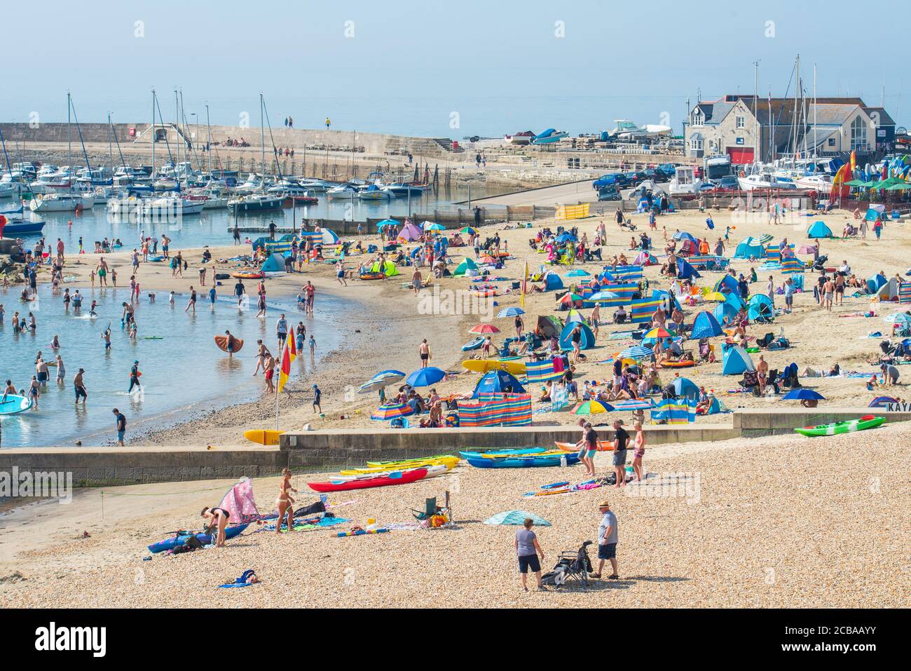 Lyme Regis, Dorset, UK. 12th Aug, 2020. UK Weather: Holidaymakers, families and sunbathers arrive early to secure a spot on the beach to bask in scorching hot sunshine at the seaside resort of Lyme Regis as the record breaking temperatures soar again. Credit: Celia McMahon/Alamy Live News Stock Photo