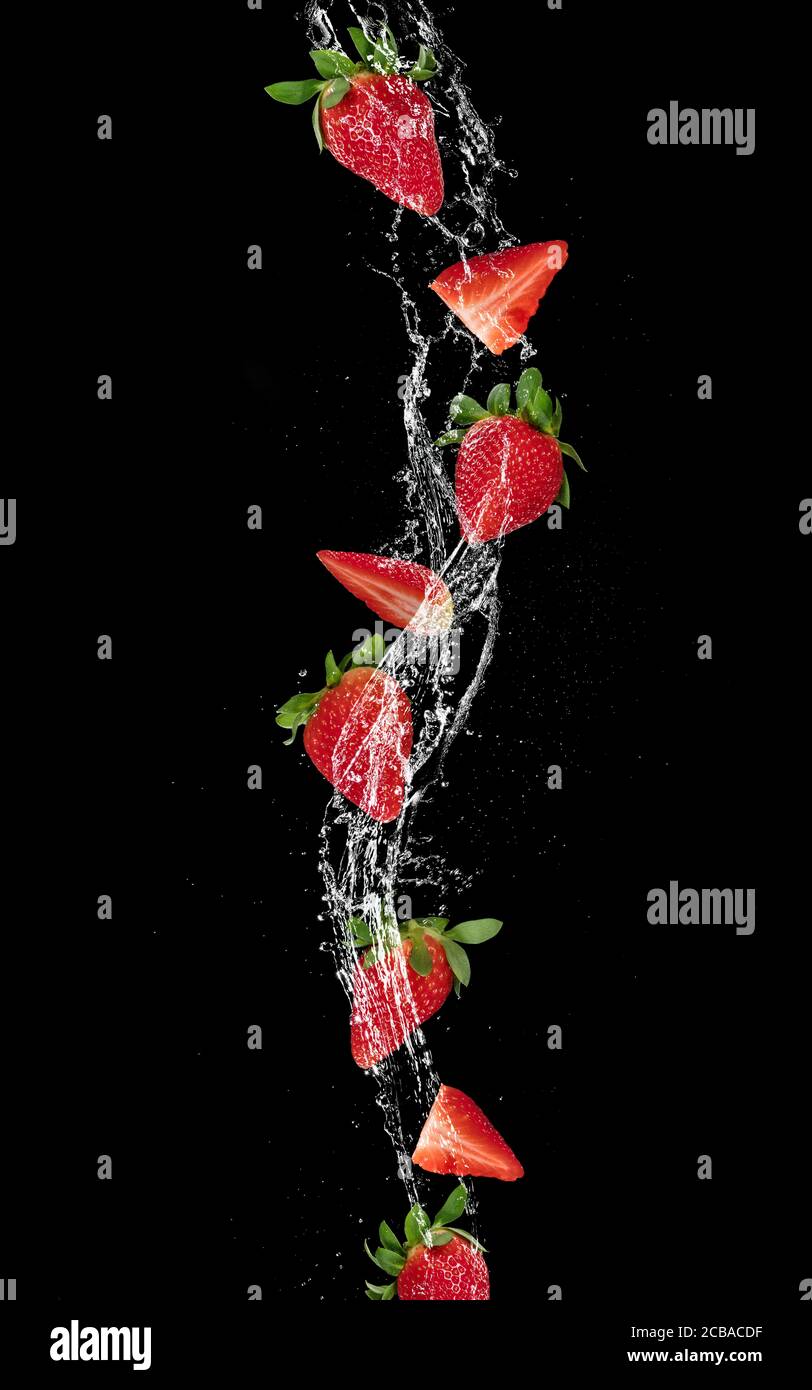 Pieces of strawberries and ice cubes falling in water splash, isolated ...