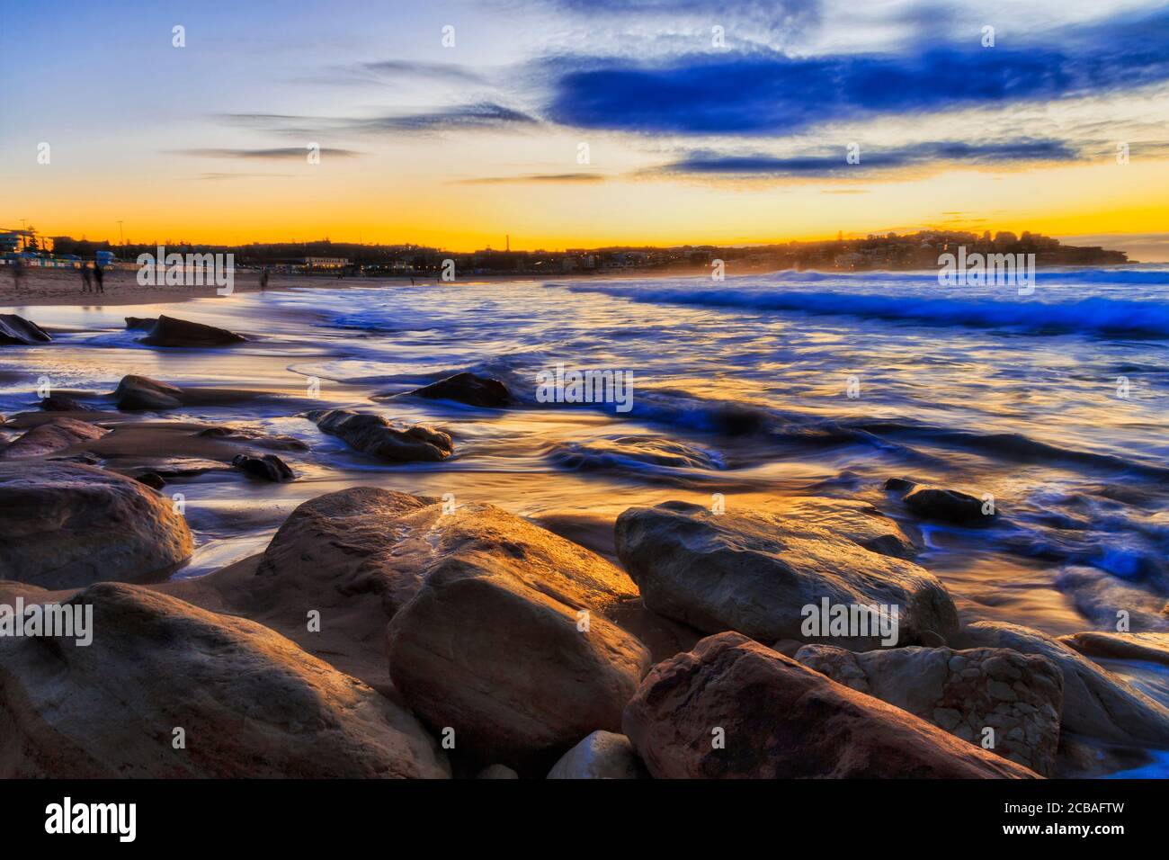 Sunrise at famous Bondi beach of Sydney on Pacific coast facing sandy beach and rocks in warm sun light. Stock Photo