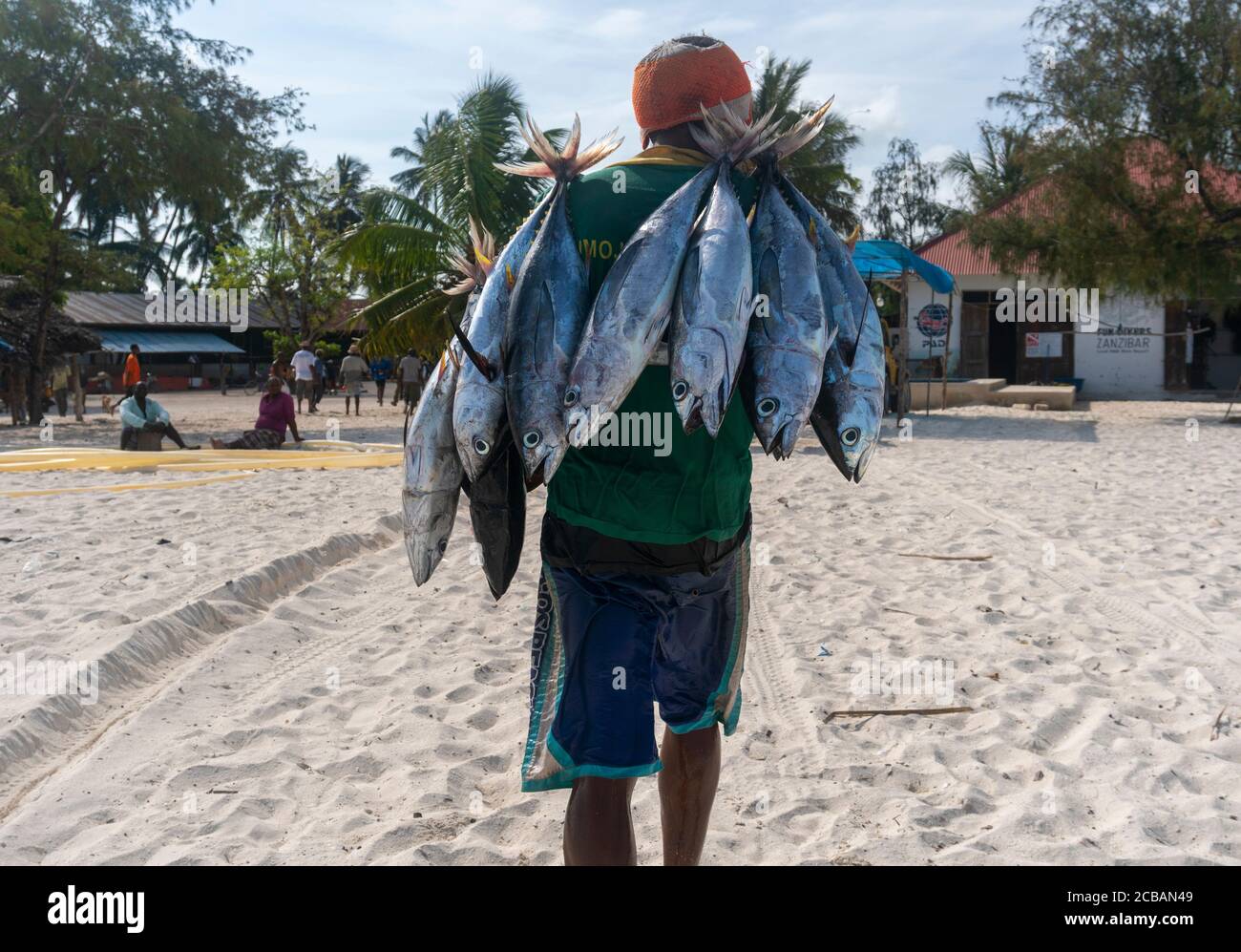Nungwi, Zanzibar, Tanzania, Africa - January 2020: Black African Man is Carrying Tuna Fish on the Street Fish Market in Nungwi village, people are Stock Photo