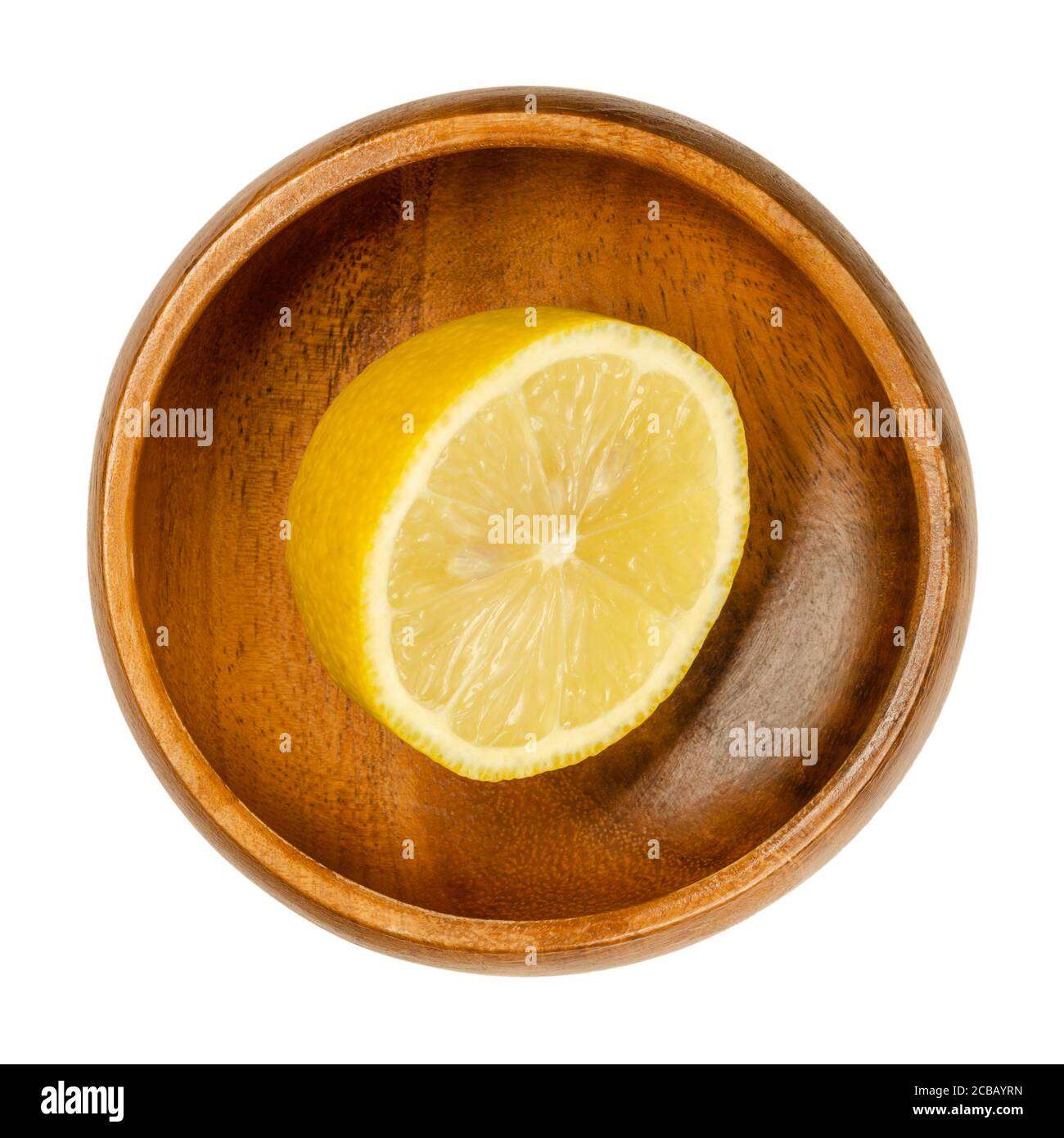 Fresh and ripe half lemon in a wooden bowl. Cut yellow edible citrus fruit, Citrus limon. Lemon juice is used for culinary purposes and for cleaning. Stock Photo