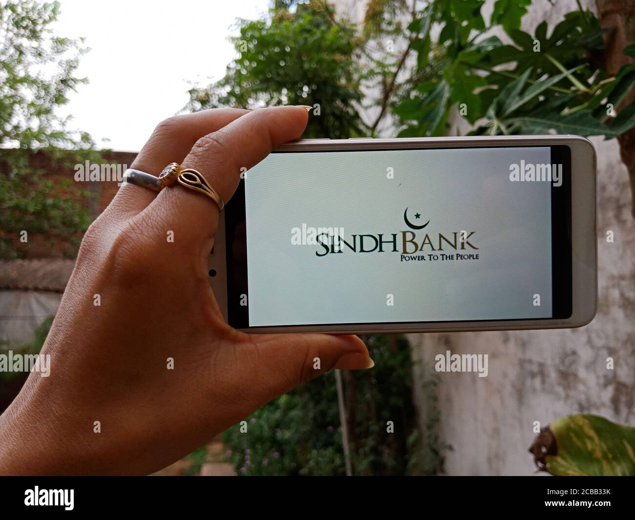 DISTRICT KATNI, INDIA - JUNE 02, 2020: An indian woman holding smart phone with displaying Sindh Bank Limited logo on screen, modern Pakistani schedul Stock Photo