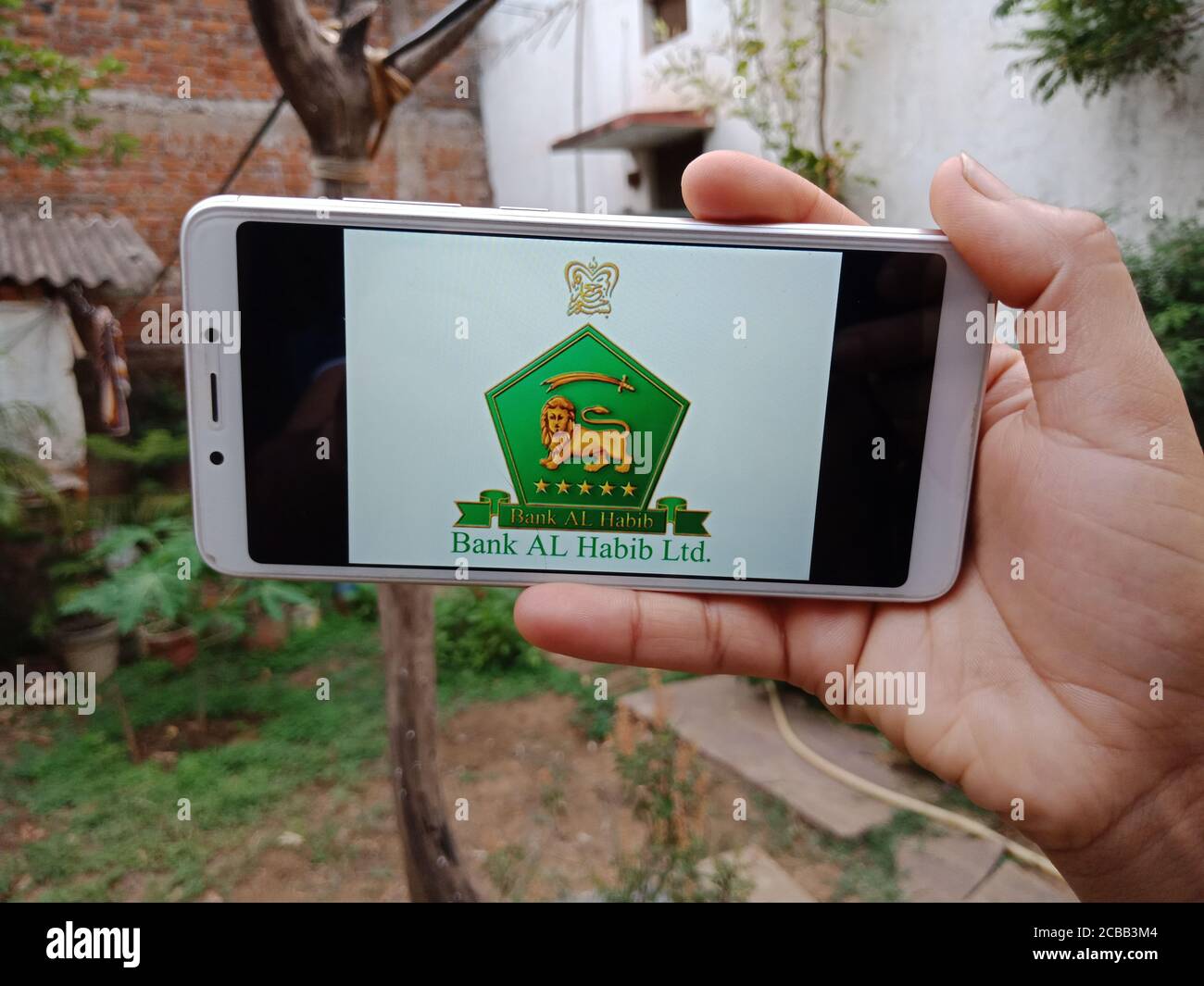 DISTRICT KATNI, INDIA - JUNE 02, 2020: An indian woman holding smart phone with displaying Bank AL Habib Commercial bank logo on screen, modern bankin Stock Photo